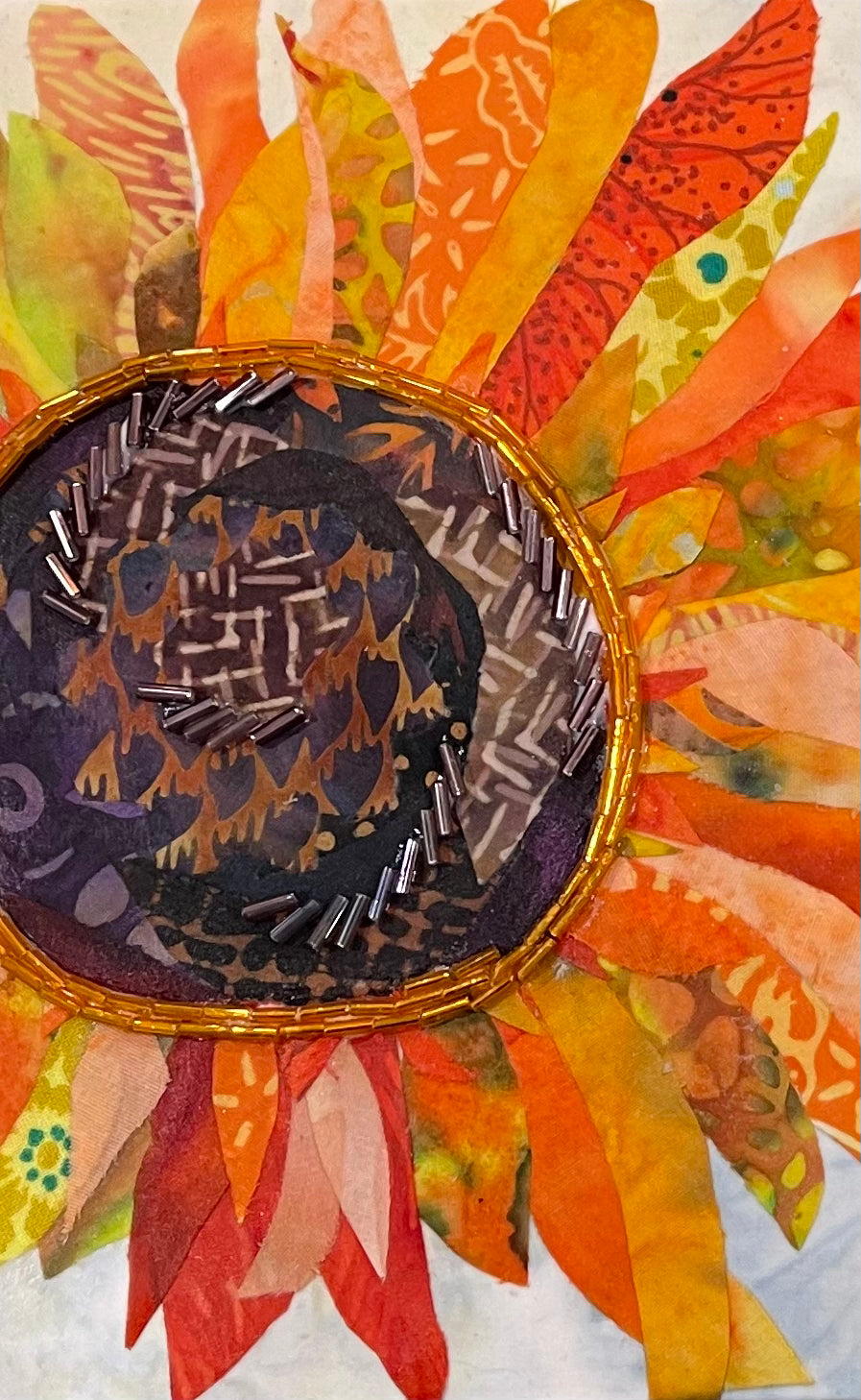 Floral artwork made with layered fabric and mixed media, featuring a sunflower bloom in warm yellow and amber tones with textured dimensional beaded details