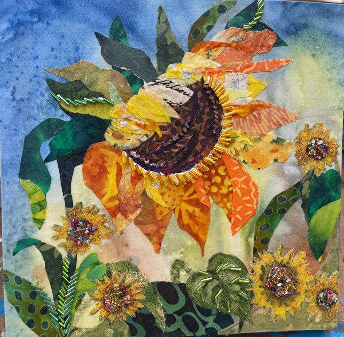Floral artwork made with layered fabric and mixed media, featuring sunflower form in golden yellow and soft neutral tones with textured beaded surface