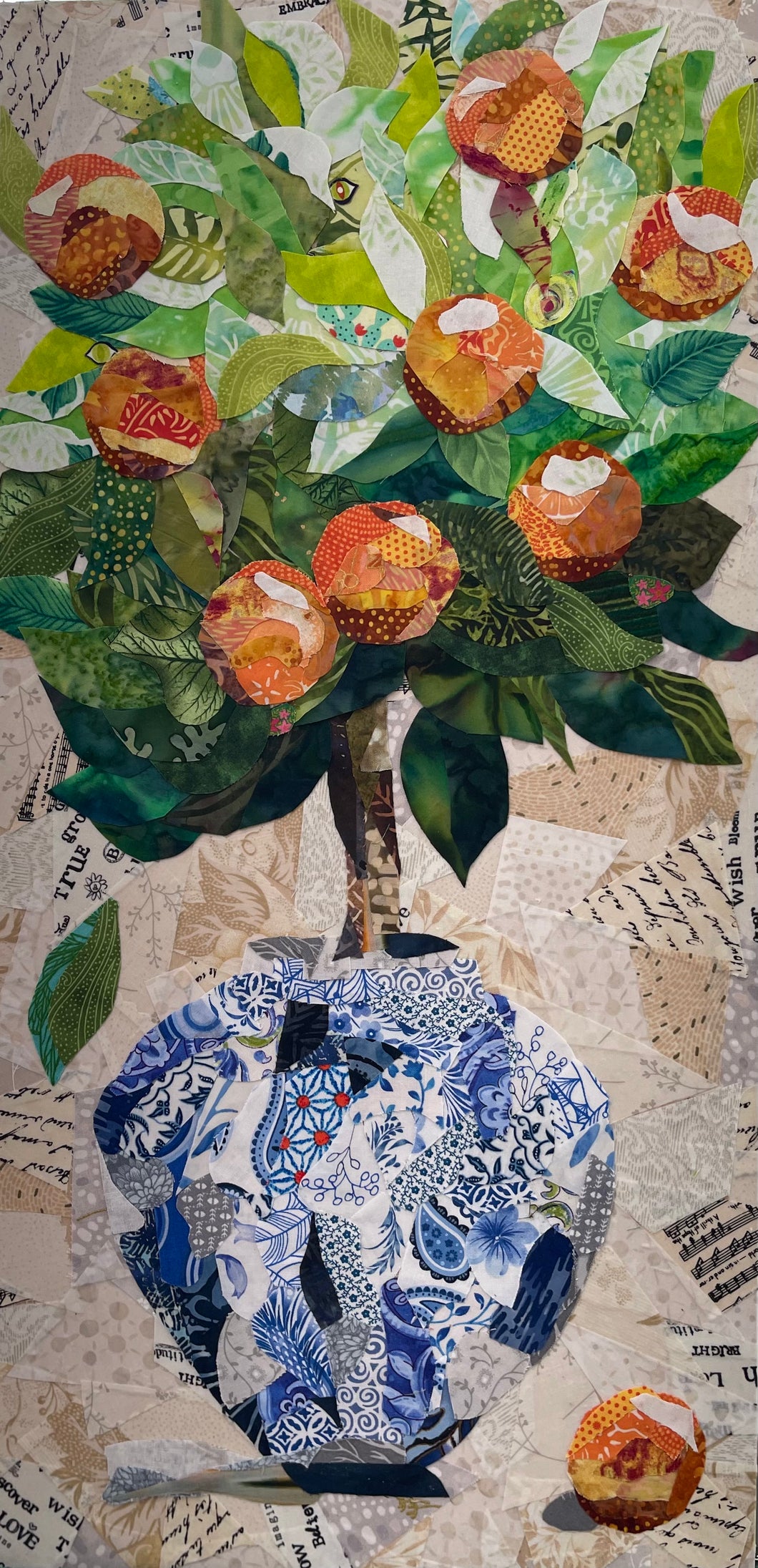 Collage-style artwork made with layered fabric and mixed media with a blue and white Chinoiserie style vase, green leaves, and oranges on a neutral background. 