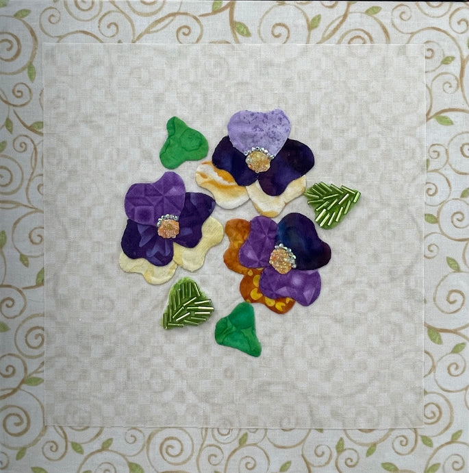 8 x 8 fabric collage artwork featuring a cluster of purple and cream flowers with beaded centers made from inherited textiles