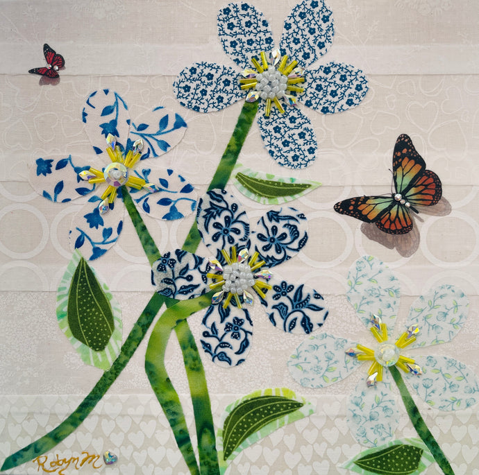 Fabric flower artwork with blue and white patterned blooms, green stems, and butterfly accents on 8x8 panel