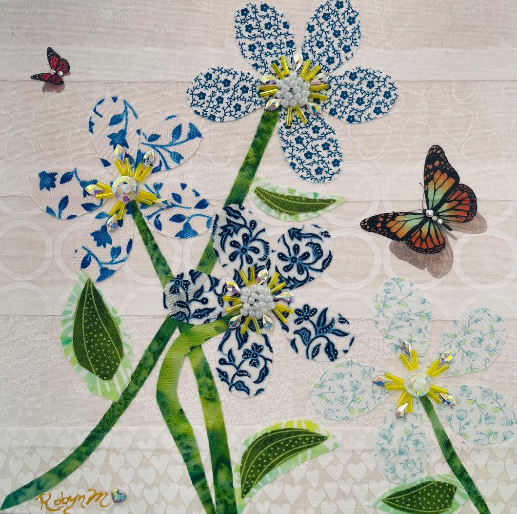 Fabric flower artwork with blue and white patterned blooms, green stems, and butterfly accents on 8x8 panel