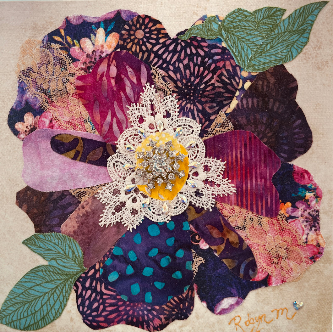 Fabric flower artwork with layered purple and pink textiles with lace and Swarovski crystal and vintage crystal broach center on 8x8 panel with green leaves
