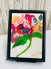Botanical fabric mixed media wall art with colorful flower, green beaded stem, and layered textile petals
