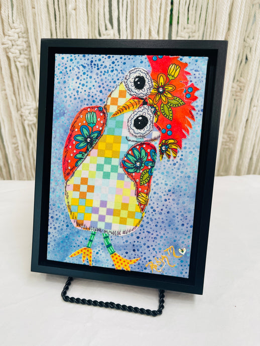 Colorful whimsical fabric collage bird with patchwork body, floral wings, and large expressive eyes on a blue textured background