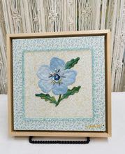 8 x 8 fabric collage artwork featuring a soft blue flower with crystal center and green stitched leaves made from inherited textiles
