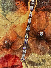 Close-up of red and coral poppies with Swarovski crystal centers cascading down a textured gold leaf panel.