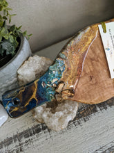 close up abstract teal and gold resin cheeseboard with crystals