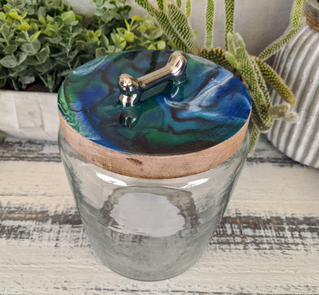 clear glass dog treat canister with wood lid coated in blue green white bronze resin with silver bone