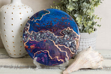abstract fluid acrylic resin painting with vibrant blue deep magenta and gold colors with stones